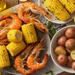 A large rustic platter filled with succulent pink shrimp, golden corn on the cob, tender red potatoes, and fresh lemon wedges, all coated in Zatarain's signature seasoned spices.