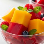 Colorful high-protein jello cubes made with fruit puree and collagen protein, served in glass bowls with fresh berries and mint garnish