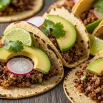 Quinoa lentil tacos filled with plant-based protein, topped with avocado, cilantro, and fresh vegetables on a rustic wooden table